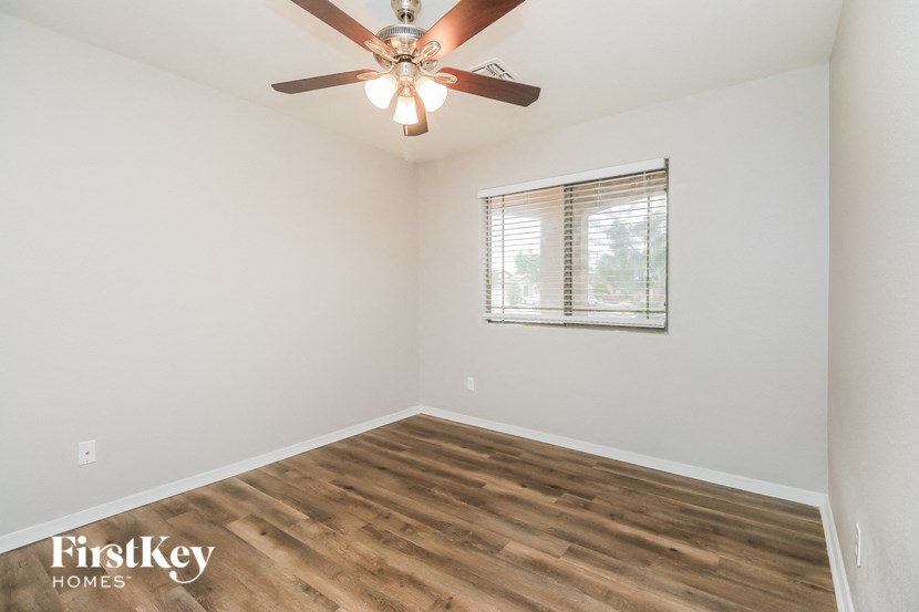the spacious living room with wood flooring and a ceiling fan