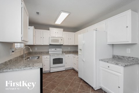 A kitchen with white cabinets and appliances.