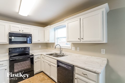 A kitchen with a black oven and white cabinets.