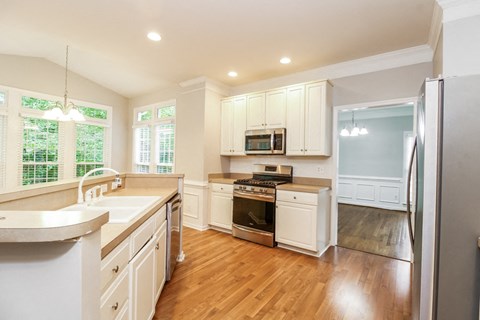 A kitchen with white cabinets and a wooden floor.