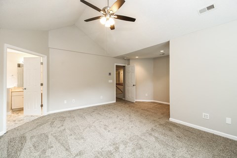 A spacious room with a ceiling fan and carpeted floor.