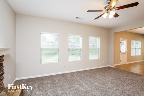 a living room with a carpet and a ceiling fan