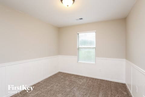 a bedroom with white walls and carpet and a window