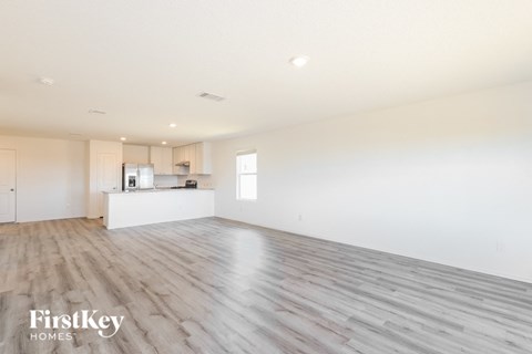A spacious empty room with wooden flooring and white walls.