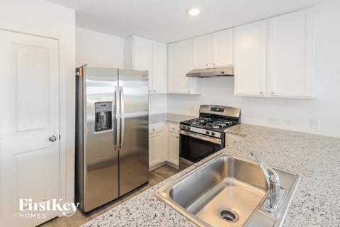 A kitchen with a stainless steel refrigerator, stove, and sink.