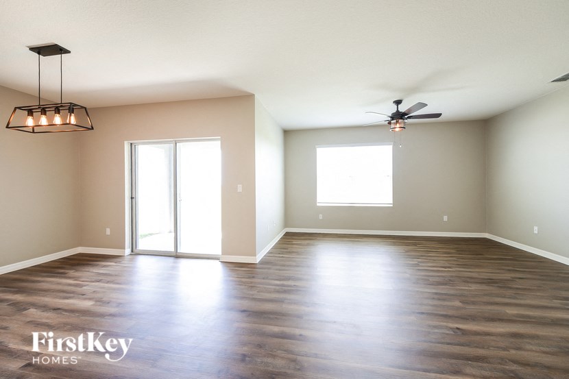 an empty living room with wood floors and a ceiling fan