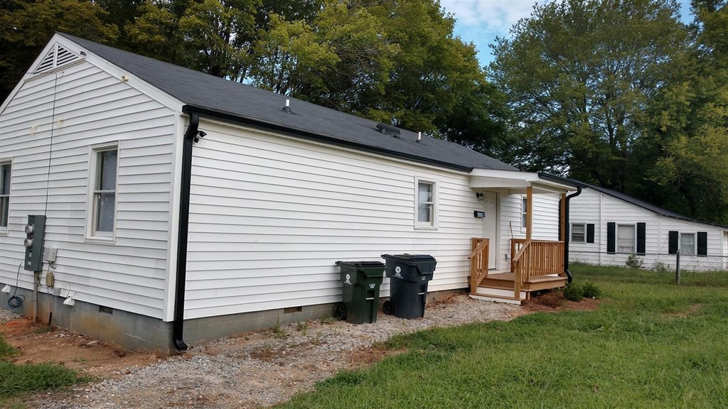 the side of a white house with a porch and a deck