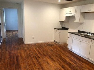 a kitchen with a wooden floor and white cabinets