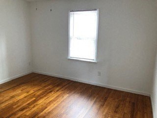 an empty room with a window and wooden floors