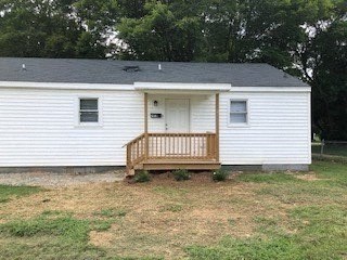 a small white house with a porch in a field