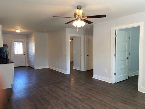 A living room with a ceiling fan and hardwood floors.