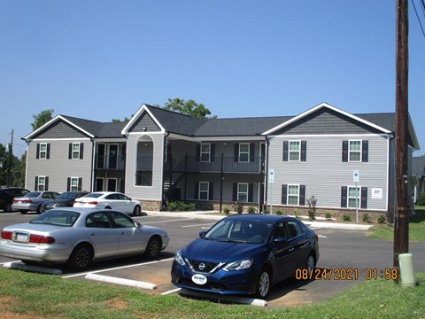 A blue car is parked in front of a grey building.