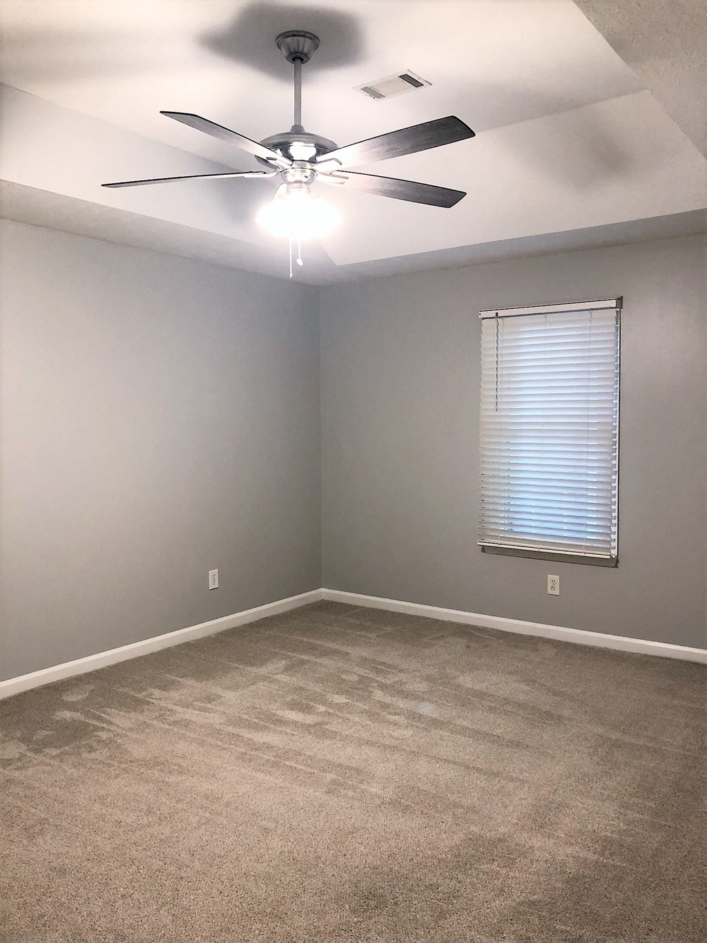an empty room with a ceiling fan and a window