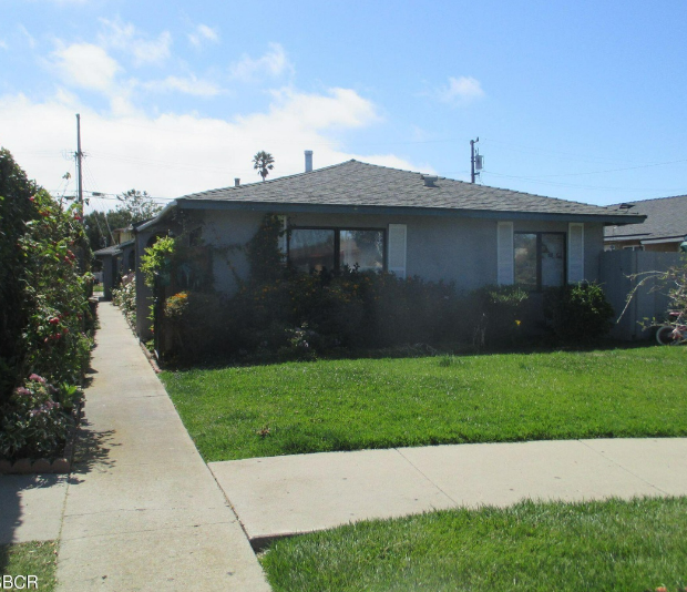 A house with a grey roof and a green lawn in front.