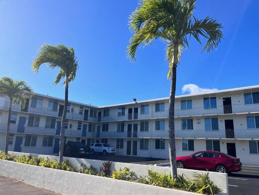 an apartment building with three palm trees in front of it