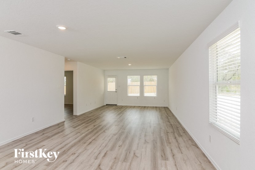 a spacious living room with white walls and wood floors