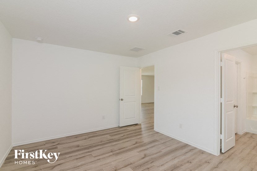 a spacious living room with white walls and wood flooring