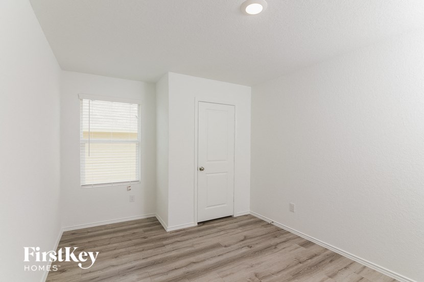 a bedroom with white walls and wood floors and a white door