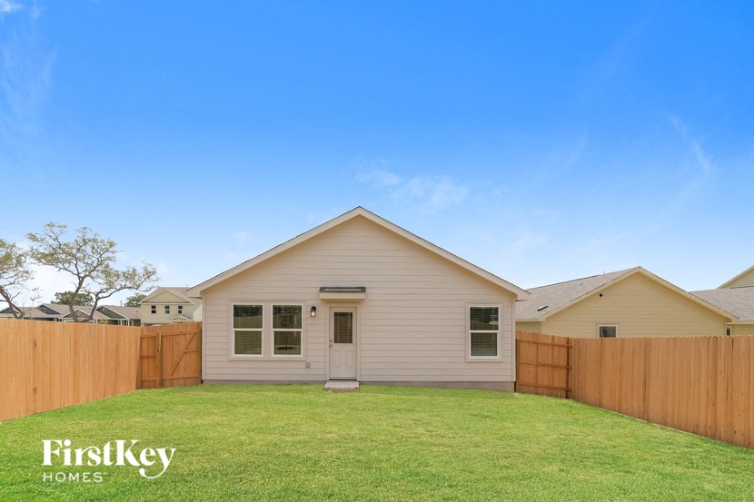 a small white house with a yard and a wooden fence