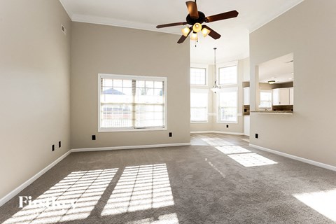A spacious room with a ceiling fan and large windows.