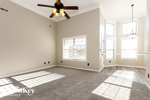A spacious room with a ceiling fan and large windows.