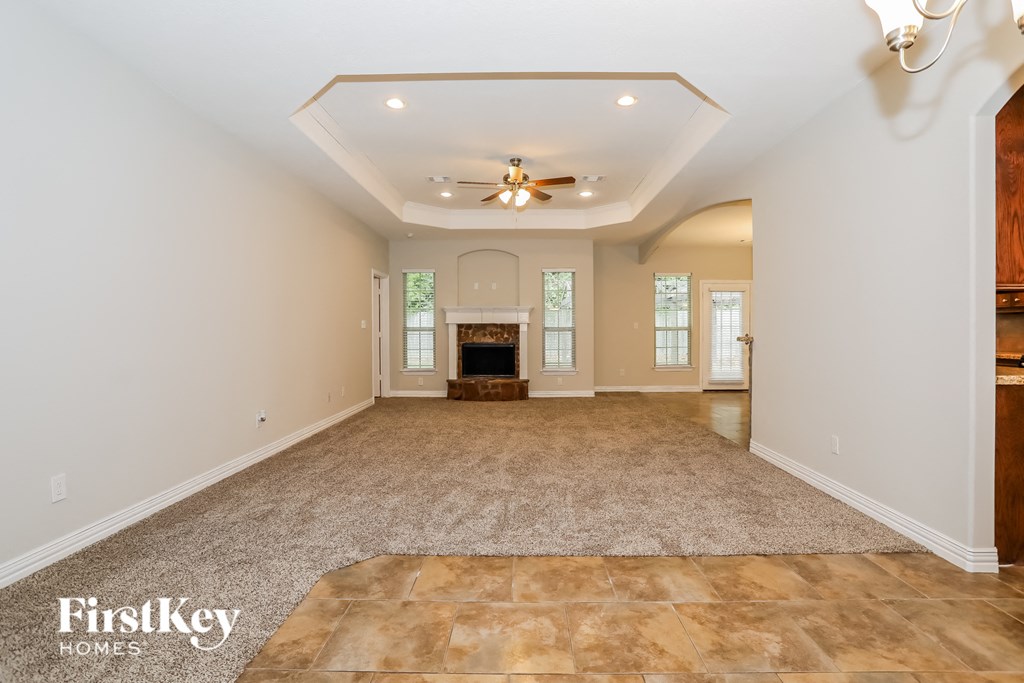 an empty living room with a fireplace and a ceiling fan