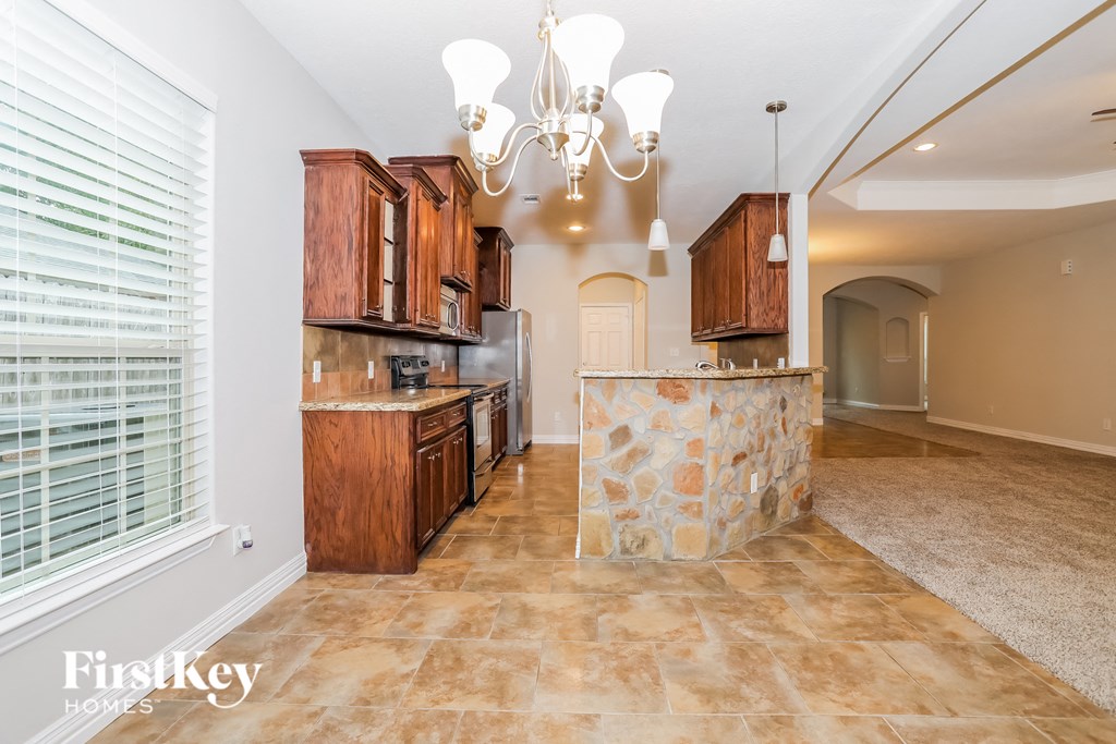 a kitchen with wood cabinets and a marble counter top