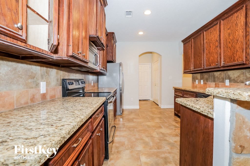 a kitchen with wood cabinets and black appliances and marble counter tops