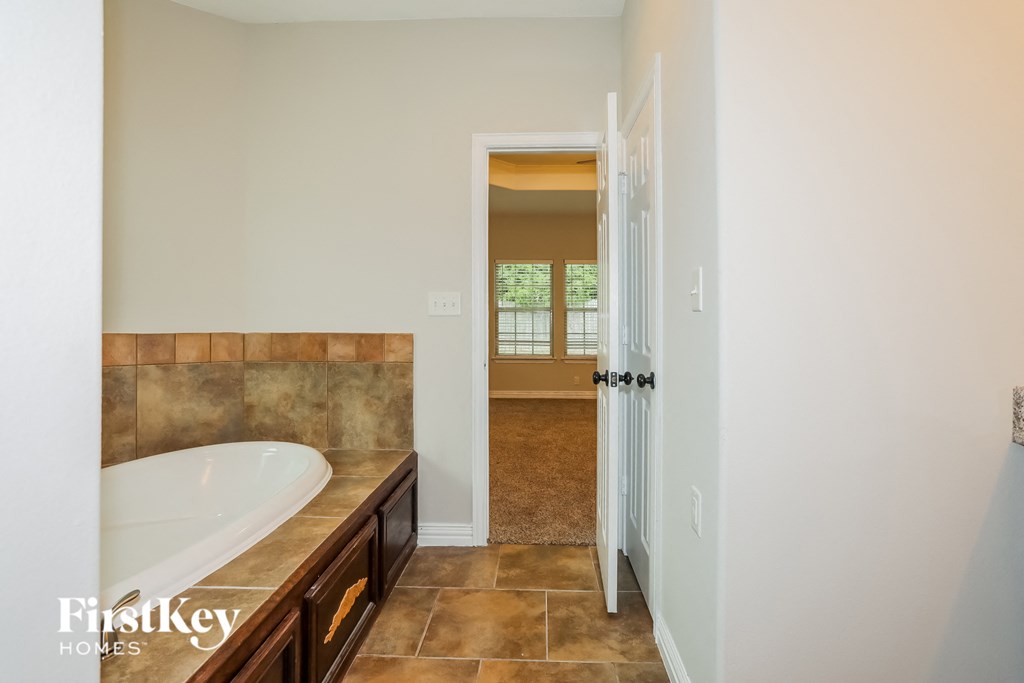 a master bathroom with a large tub and a shower and a door to a bedroom