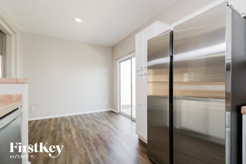 A kitchen with a stainless steel refrigerator and wooden flooring.