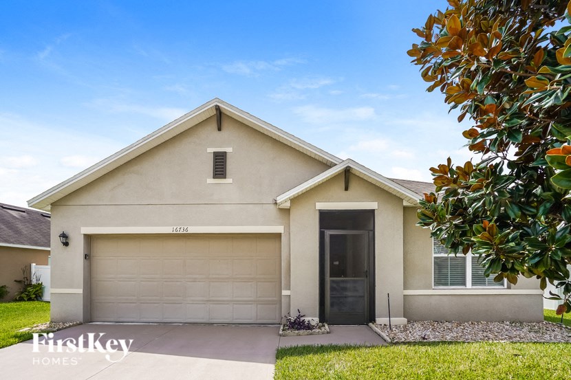 a beige house with a garage door and a tree