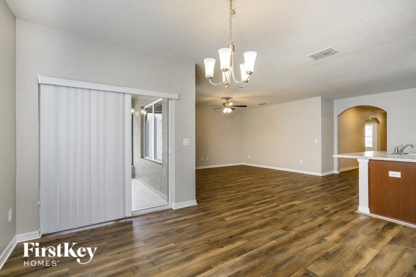 a living room and dining room with wood flooring and a door to the kitchen