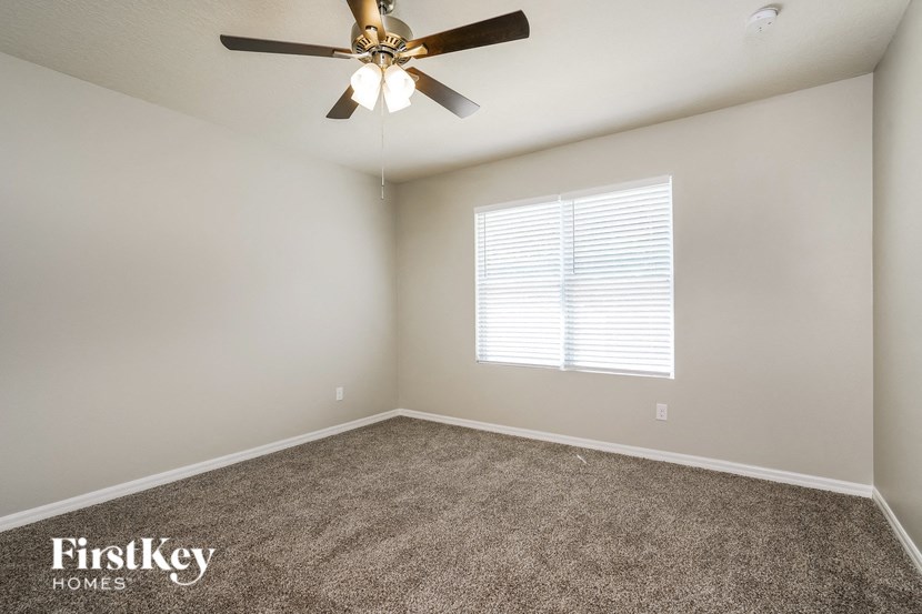 an empty room with a ceiling fan and a window