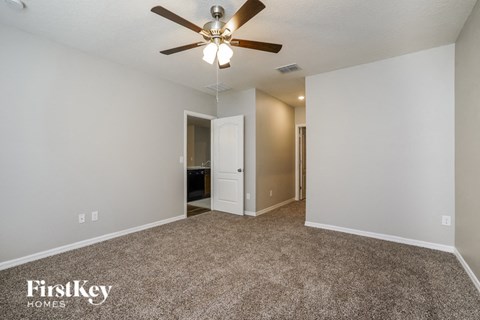 a spacious living room with carpet and a ceiling fan