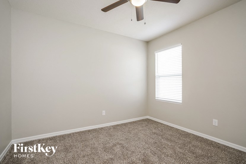 an empty room with a ceiling fan and a window