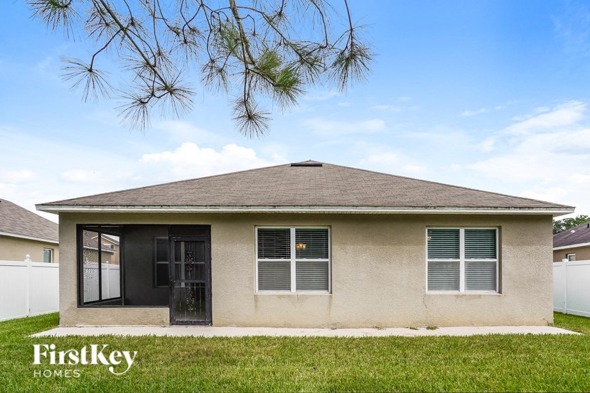a small tan house with a yard and a tree