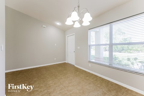 a spacious dining room with a large window and a chandelier