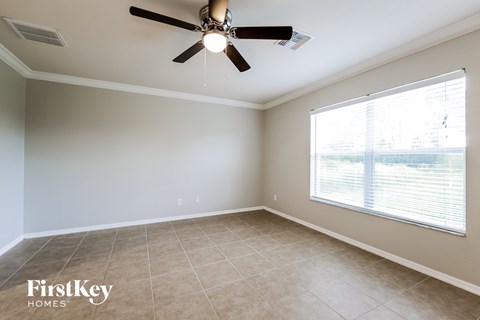 a living room with a large window and a ceiling fan