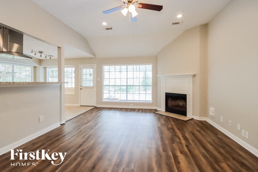 an empty living room with a fireplace and a ceiling fan