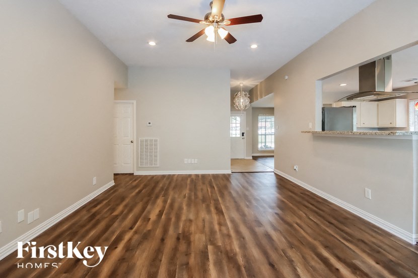 an empty living room with wood flooring and a ceiling fan
