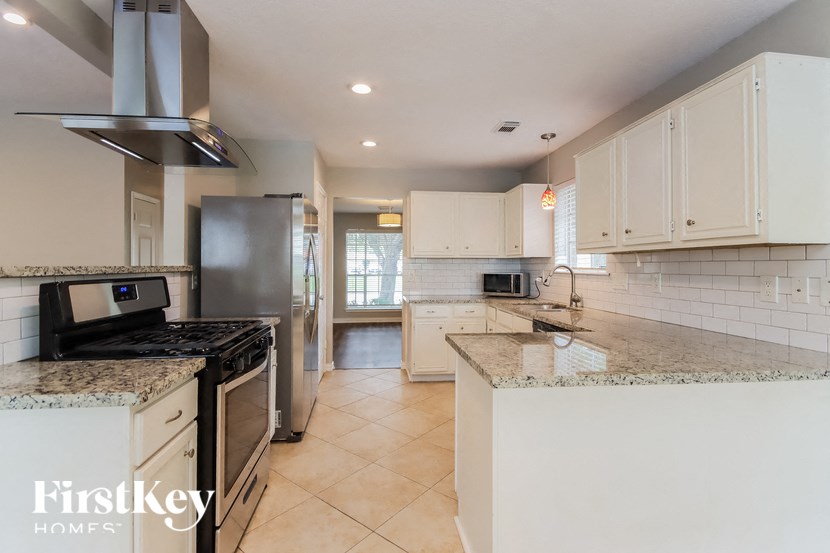 a kitchen with white cabinets and granite counter tops and a stove and refrigerator