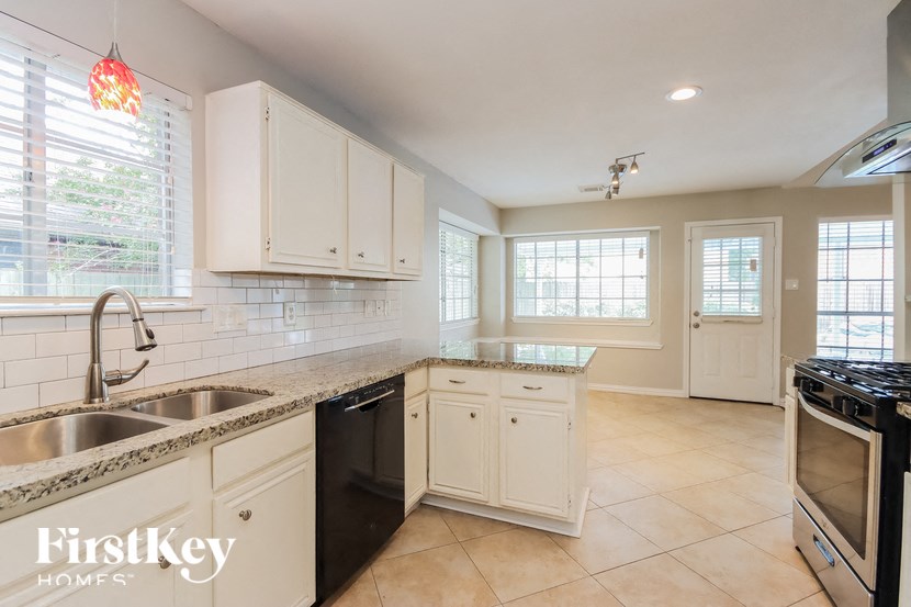 a kitchen with white cabinets and a sink and a stove