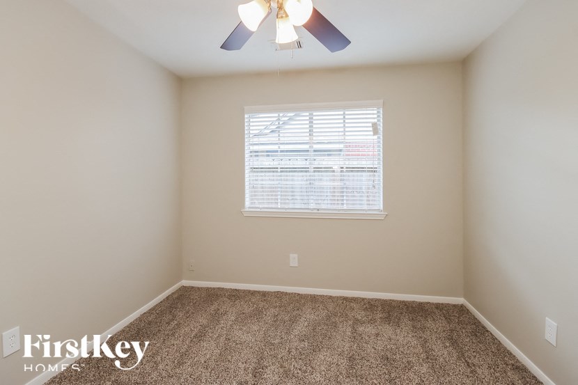 the spacious bedroom with carpeted flooring and a ceiling fan