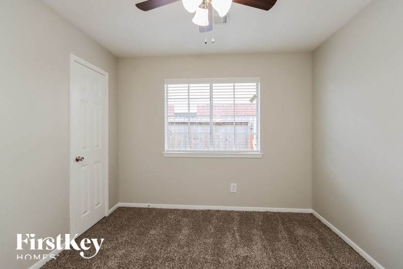 a bedroom with carpet and a window and a ceiling fan