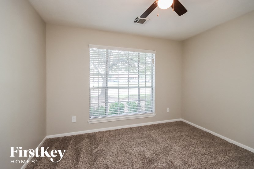 a bedroom with carpet and a large window with blinds