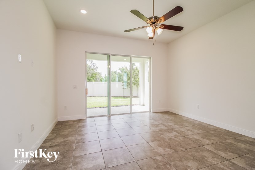 A room with a ceiling fan and sliding glass doors.