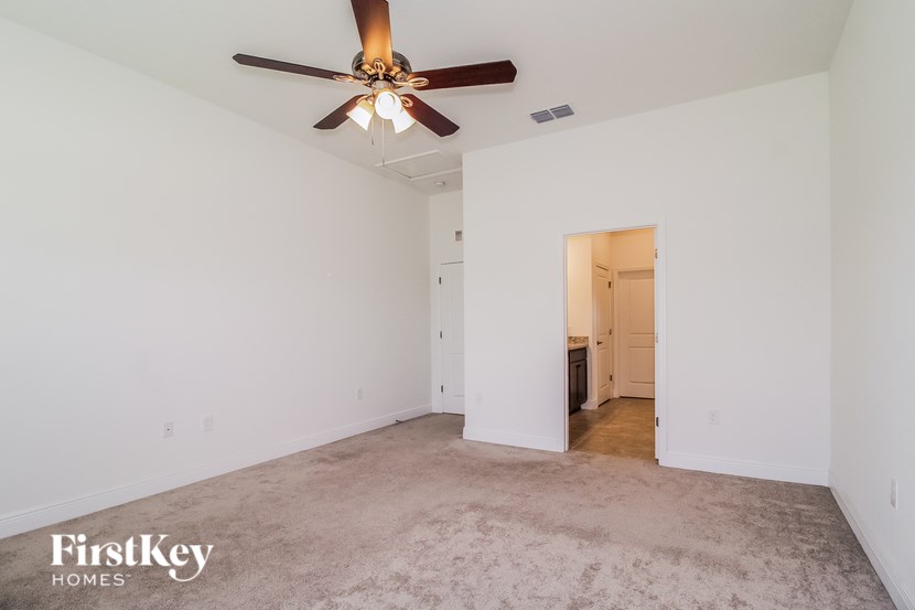 A spacious room with a ceiling fan and a carpeted floor.