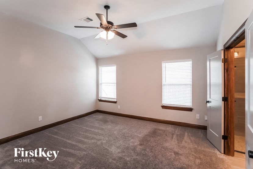 an empty room with a ceiling fan and two windows