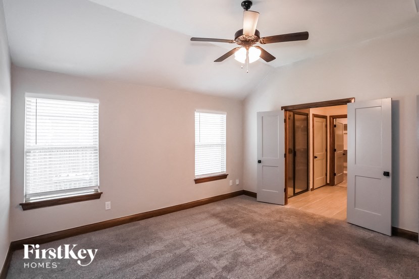 an empty living room with a ceiling fan and a closet