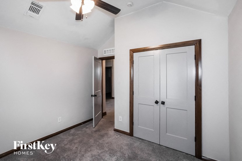 a bedroom with white walls and white closets and a door to a hallway